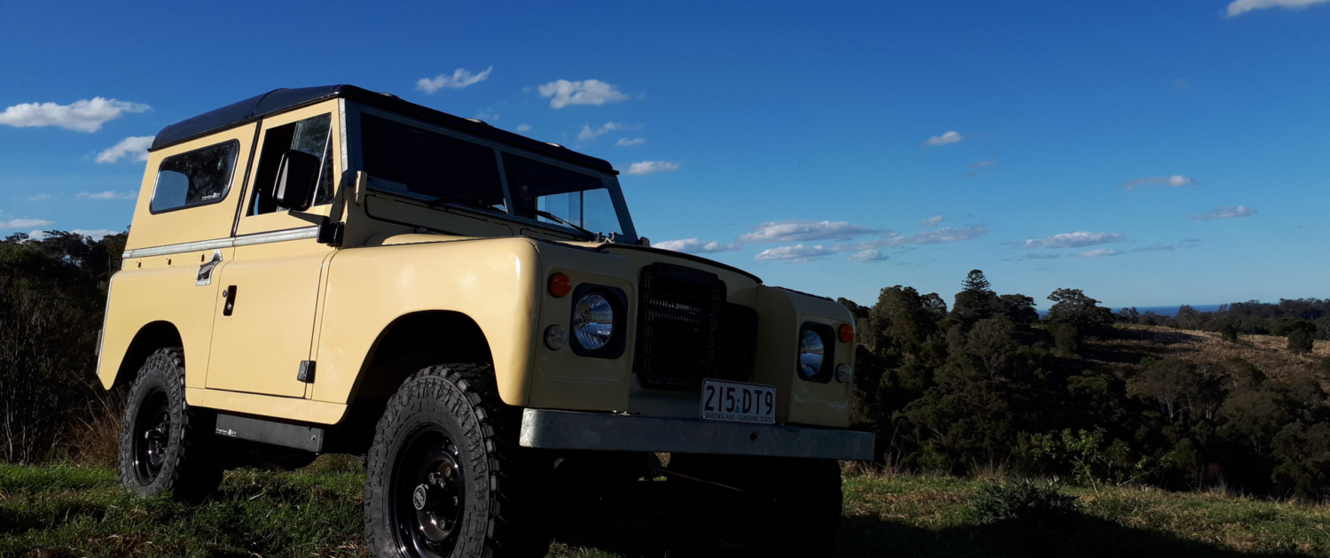 The electric 1973 Series 2 Land Rover at a scenic spot during a 4WD adventure.