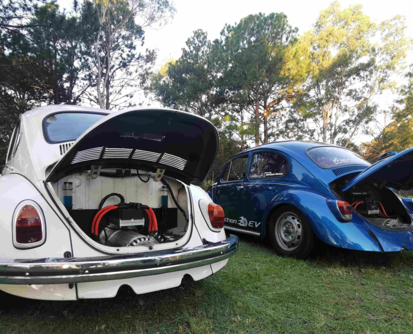 The white 1971 electric Super Beetle and Traction EV's 1968 Shop Beetle in 2021. Rear view showing the HyPer9 electric motors and speed controllers.